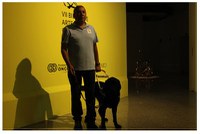 Perro guía junto a su instructor en la bienal de arte