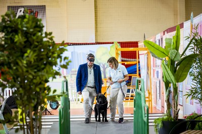 El alcalde de Azuqueca de Henares, Miguel Óscar Aparicio, con un antifaz, guiado por uno de los perros guía y una instructora.jpg