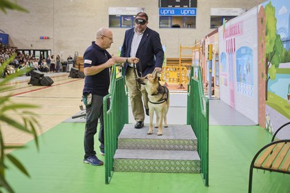 El presidente del Parlamento de Navarra, Unai Hualde, con antifaz, es guiado por uno de los perros.