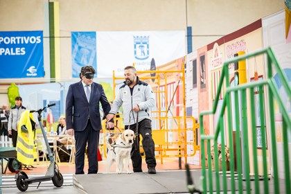 David Pérez, concejal presidente de la Junta Municipal del Distrito de Hortaleza, con antifaz, es guiado por uno de los perros