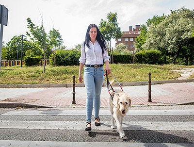 Usuaria ciega junto a su perro guía cruzando una calle 