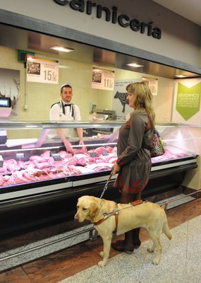 Una usuaria con su perro guía comprando en una carnicería